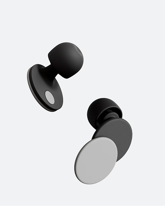 A woman resting her head back in an airplane seat. She wears Orbit Earplugs in the color Midnight Grey.