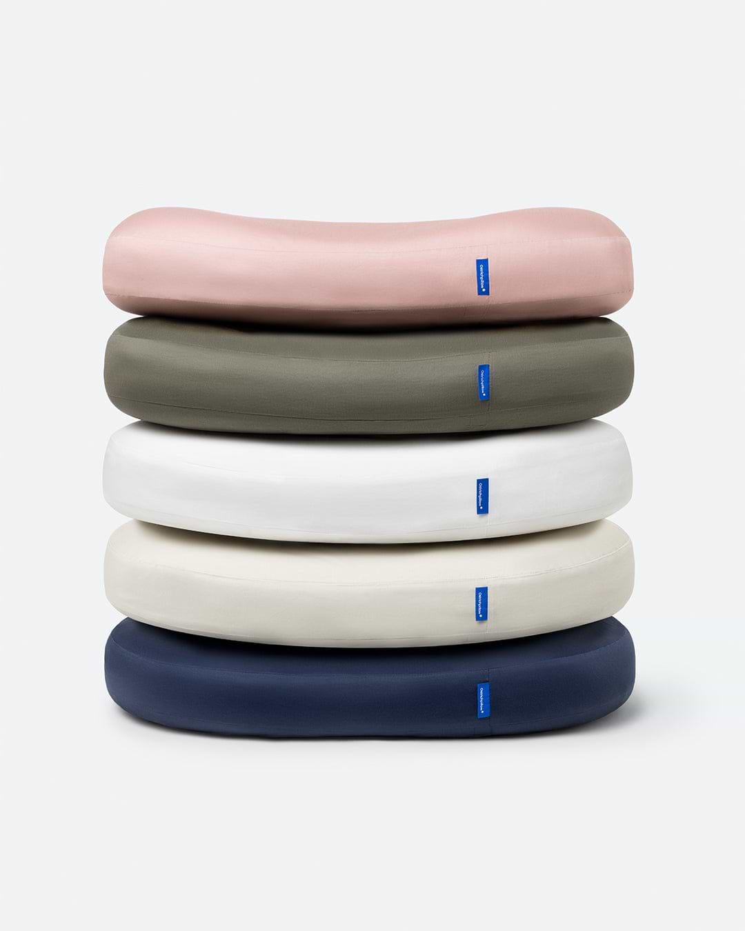A stack of Memory Foam Bed Pillows showcasing a variety of color variants including Blush Pink, Dark Olive, Powder White, Light Beige, and Dark Navy.