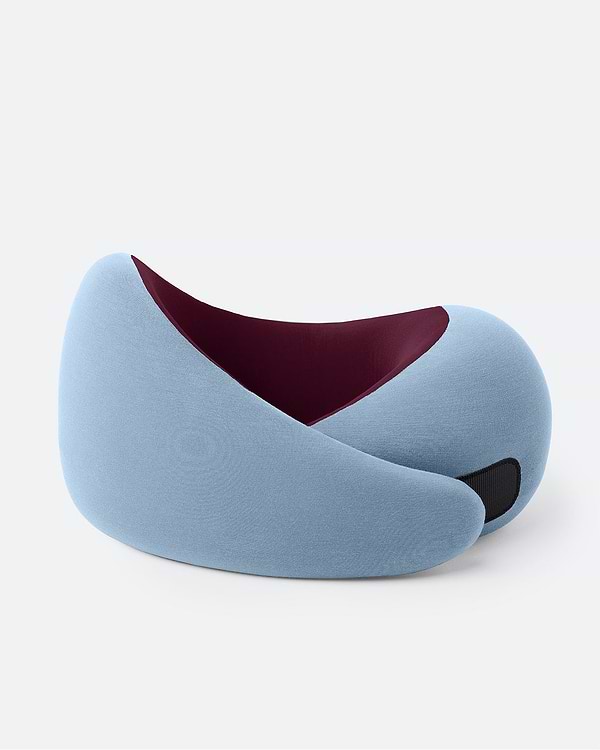 The Ostrichpillow Go Neck Pillow in color Dawn, which features a soft blue outer fabric and a burgundy inner lining, fastened by its adjustable strip.