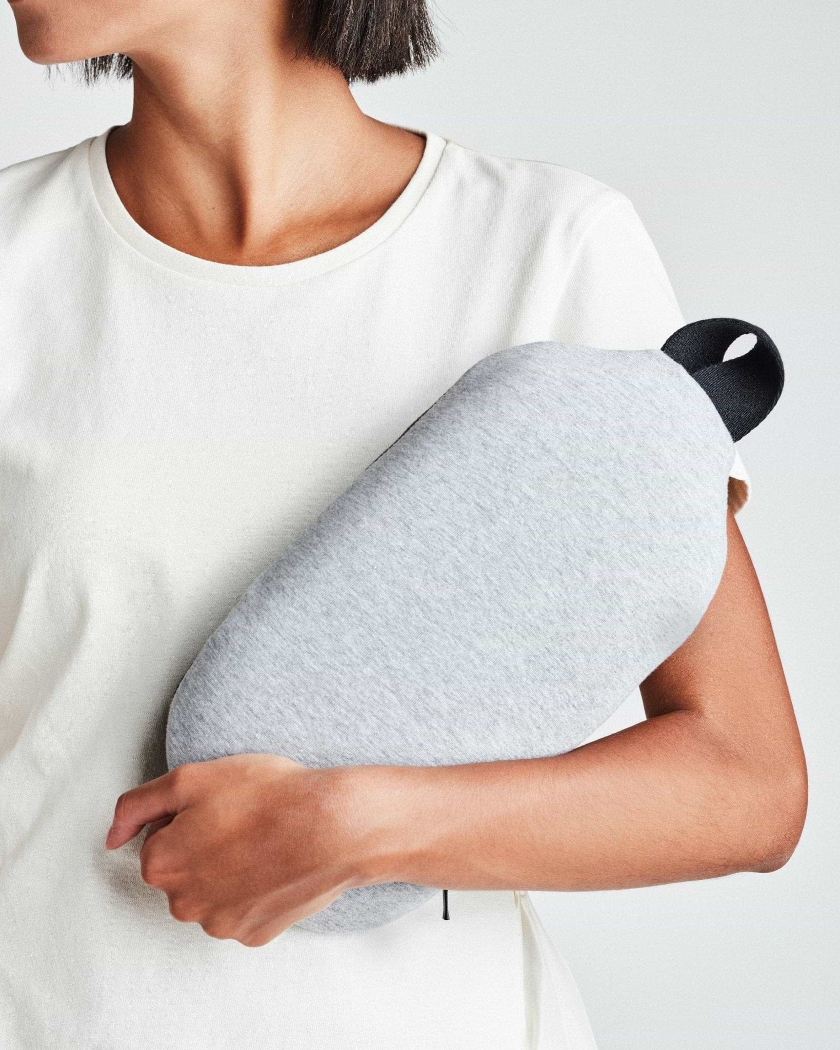 A woman holding the Ostrichpillow gray heatbag on her arm