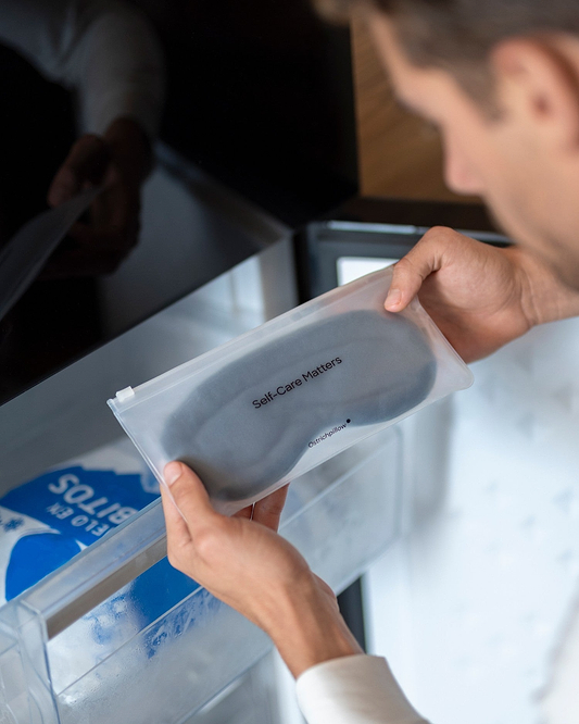 A person holds Hot & Cold Eye Mask sealed inside a frosted zipper pouch, placing it into or removing it from a freezer.