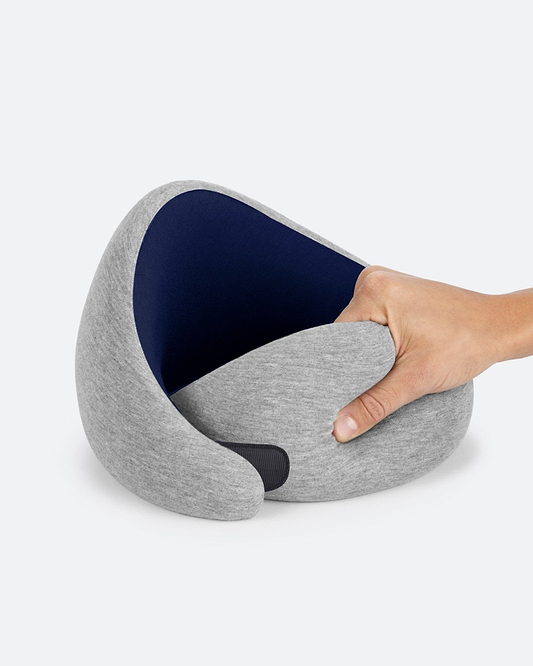 The Go Neck Pillow in Deep Blue showing its memory foam flexibility, with a light heather grey exterior and dark navy inner lining.