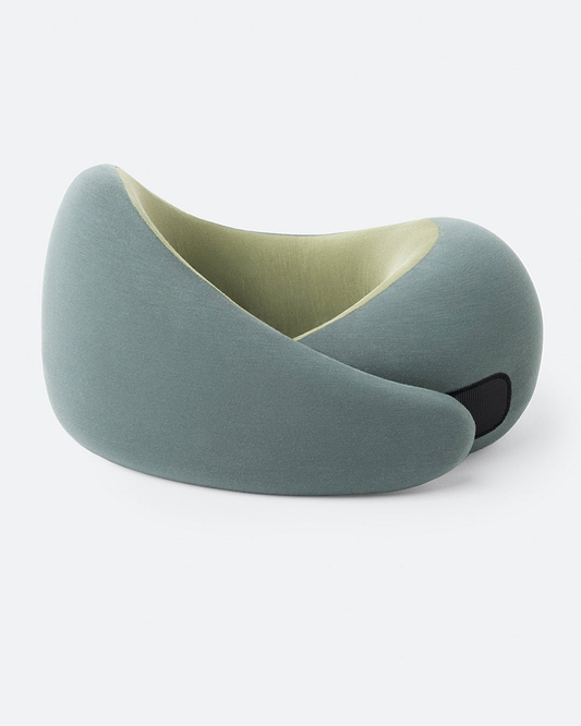 The Go Neck Pillow in the color Forest Snooze, which features a sage outer fabric and an olive green inner lining, fastened by its adjustable strip.