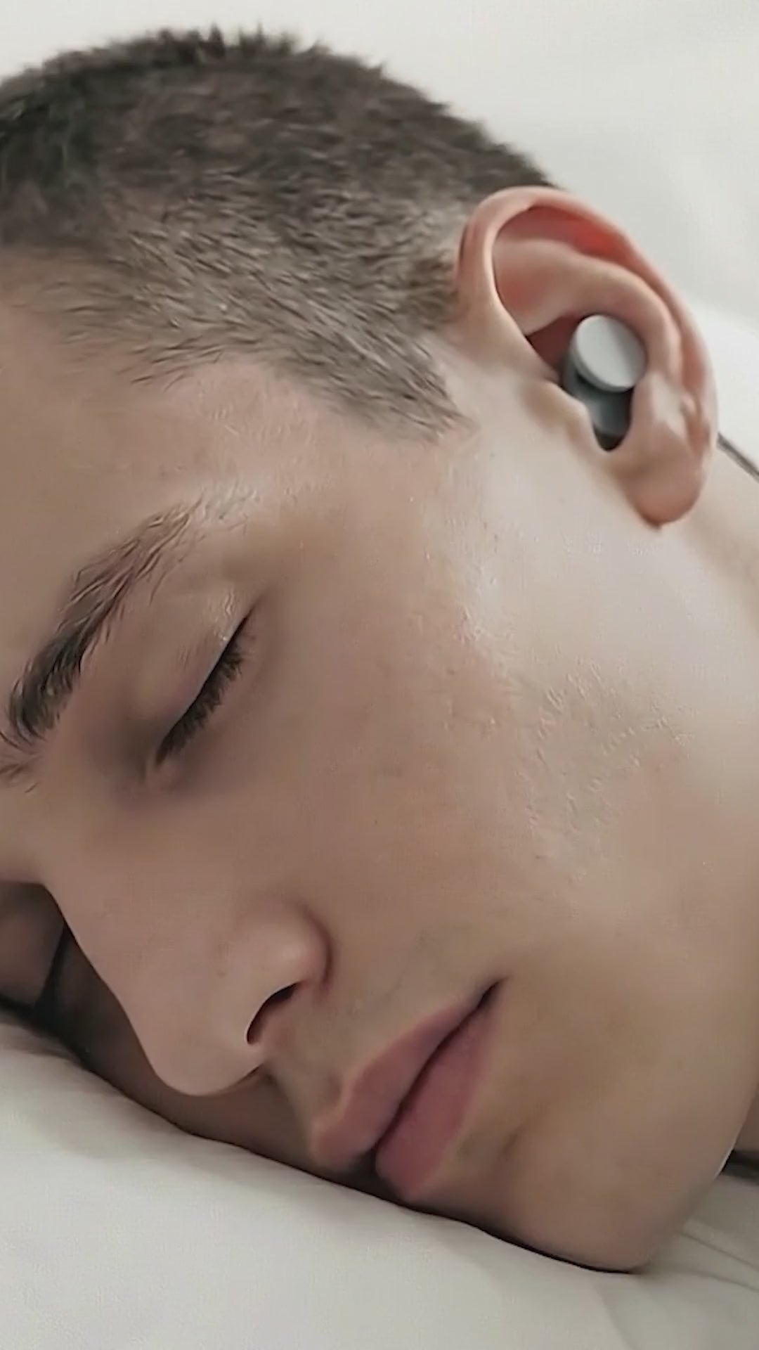 Load video: A man sleeping on his side, showing Orbit Earplugs, showing how they sit securely and how to replace the interchangeable silicone ear tips.