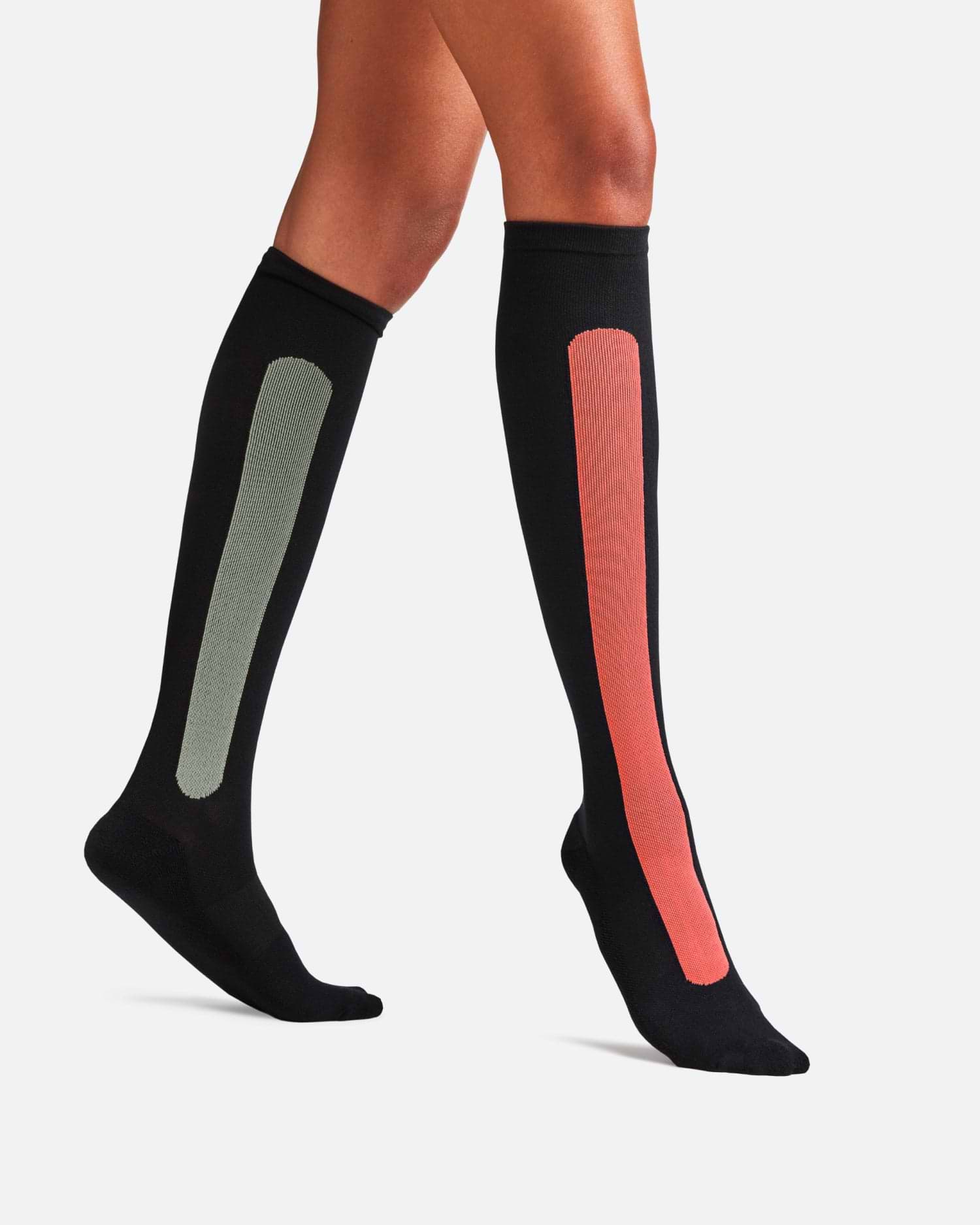 A traveler wearing Bamboo Compression Socks in the 'Sunset Red Olive Green' colorway, showing a prominent red stripe above the ankle.