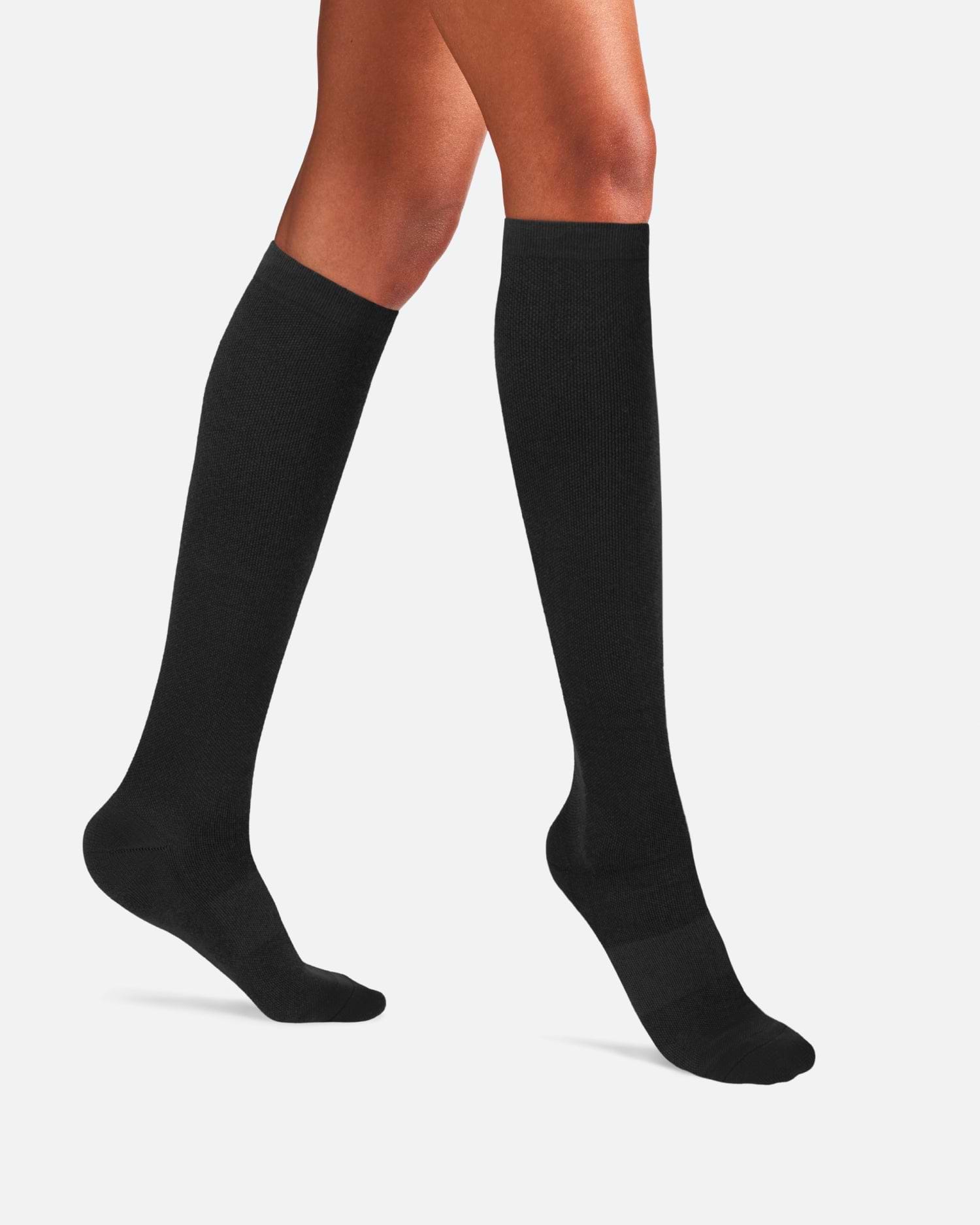 Side-profile view of a person's legs walking, wearing knee-high Ostrichpillow Bamboo Compression Socks in solid Black Eclipse.