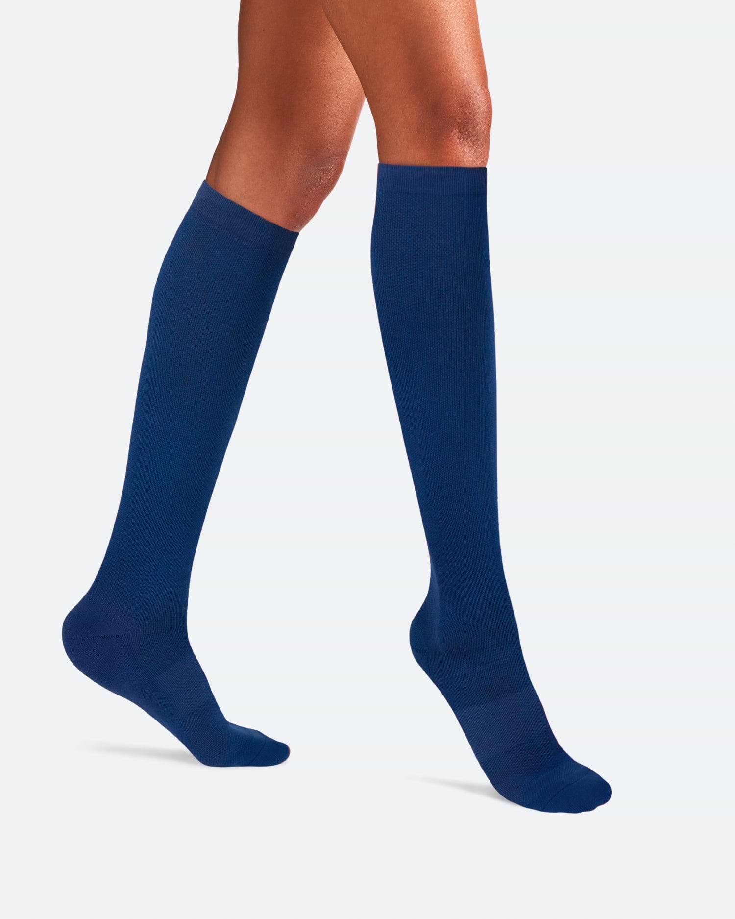 Side-profile view of a person's legs walking, wearing knee-high Ostrichpillow Bamboo Compression Socks in solid Seaside Siesta deep navy blue.