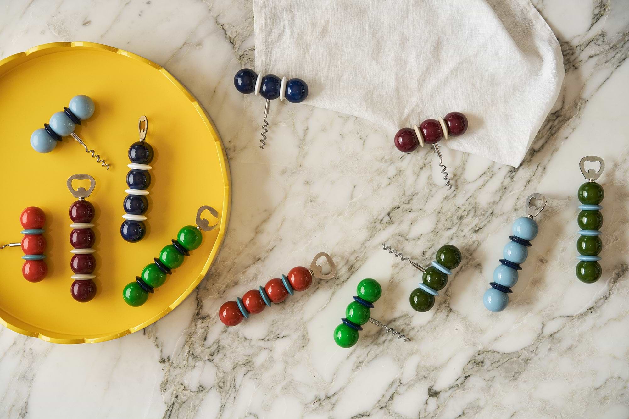 Addison Ross ball corkscrews and bottle openers in navy, red, green, light blue and burgundy laid out on marble