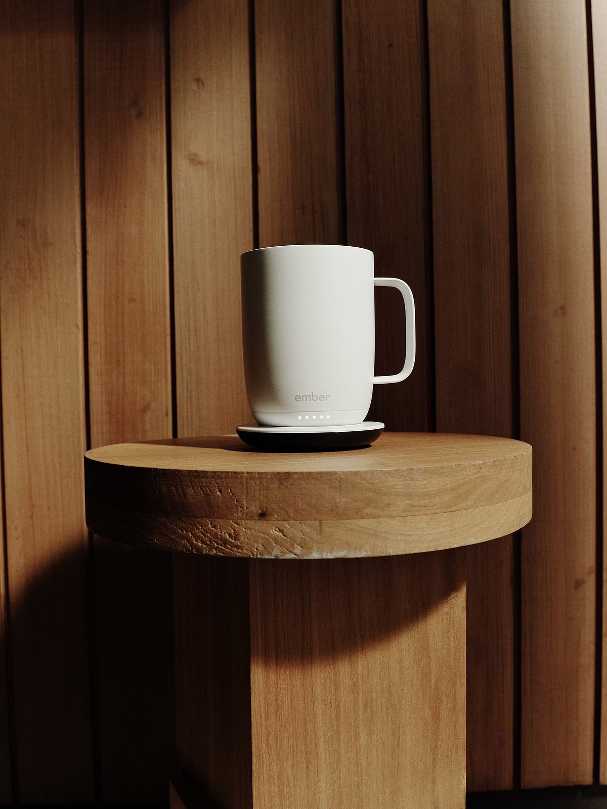 White Ember Mug 3 on its charging coaster on a wooden shelf