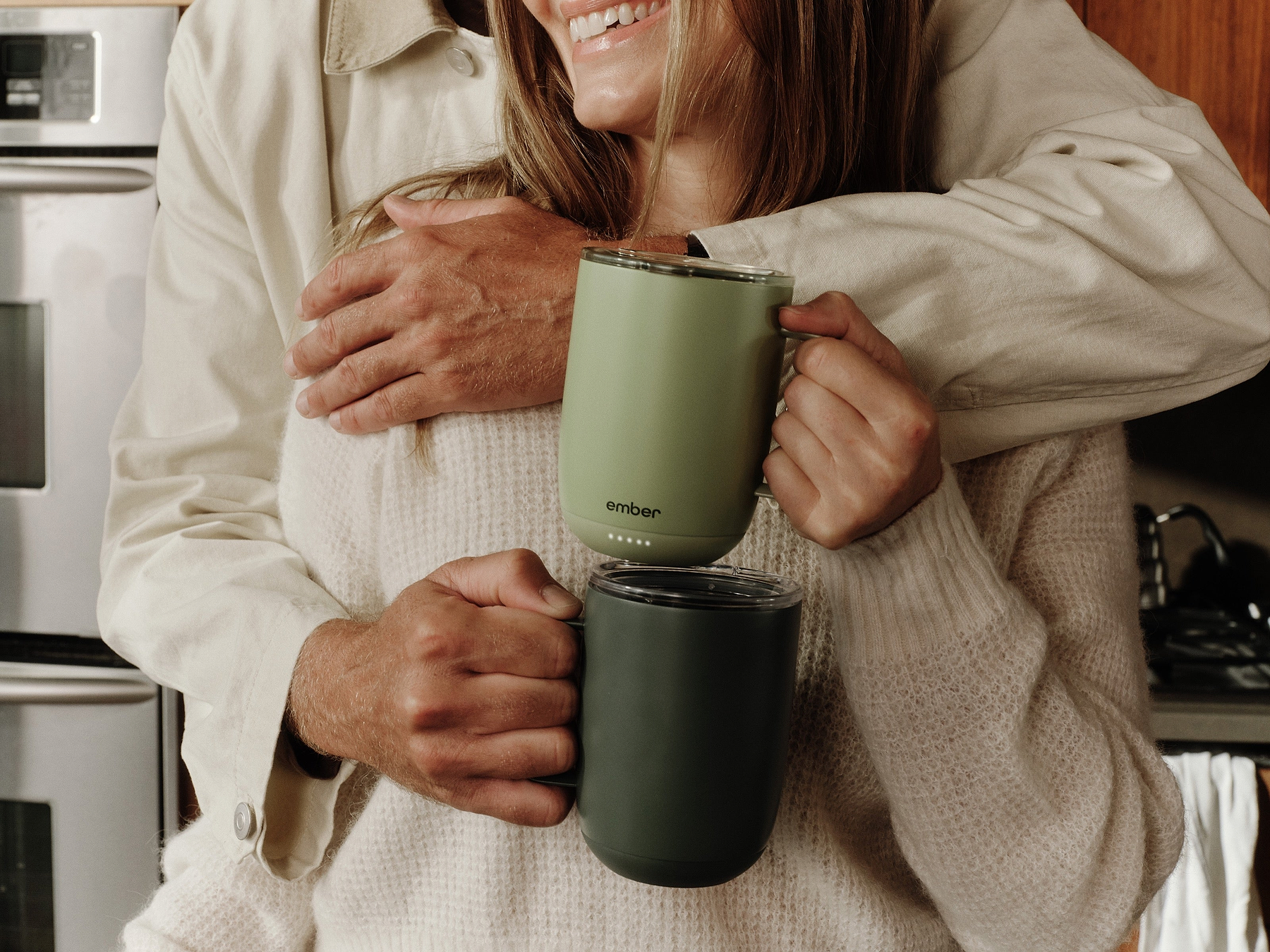 Two people sharing a warm moment with green Ember Mug 3 mugs