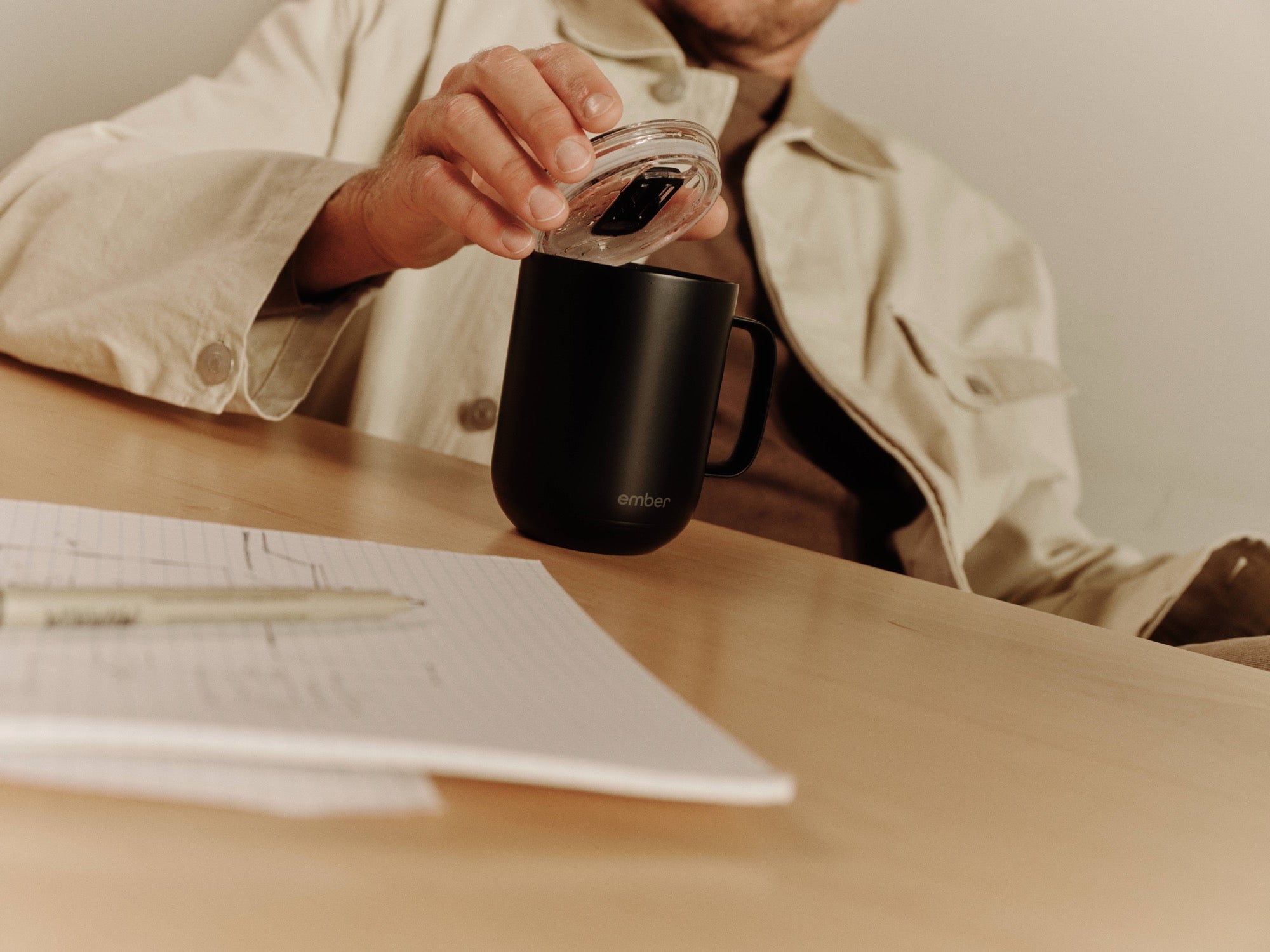 Placing the sliding lid on a black Ember Mug 3 during a coffee break at a desk
