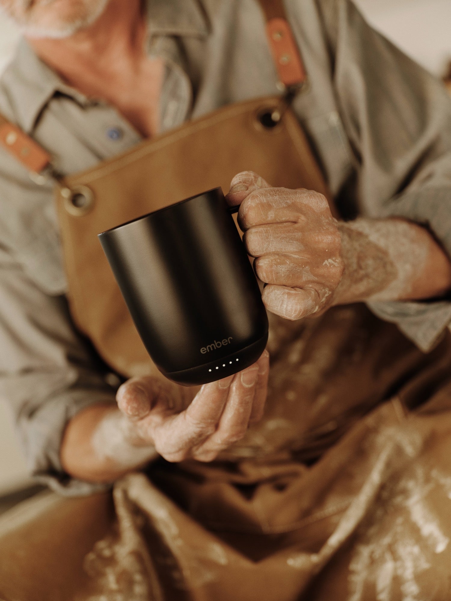 Setting the temperature on a black Ember Mug 3 in a pottery studio
