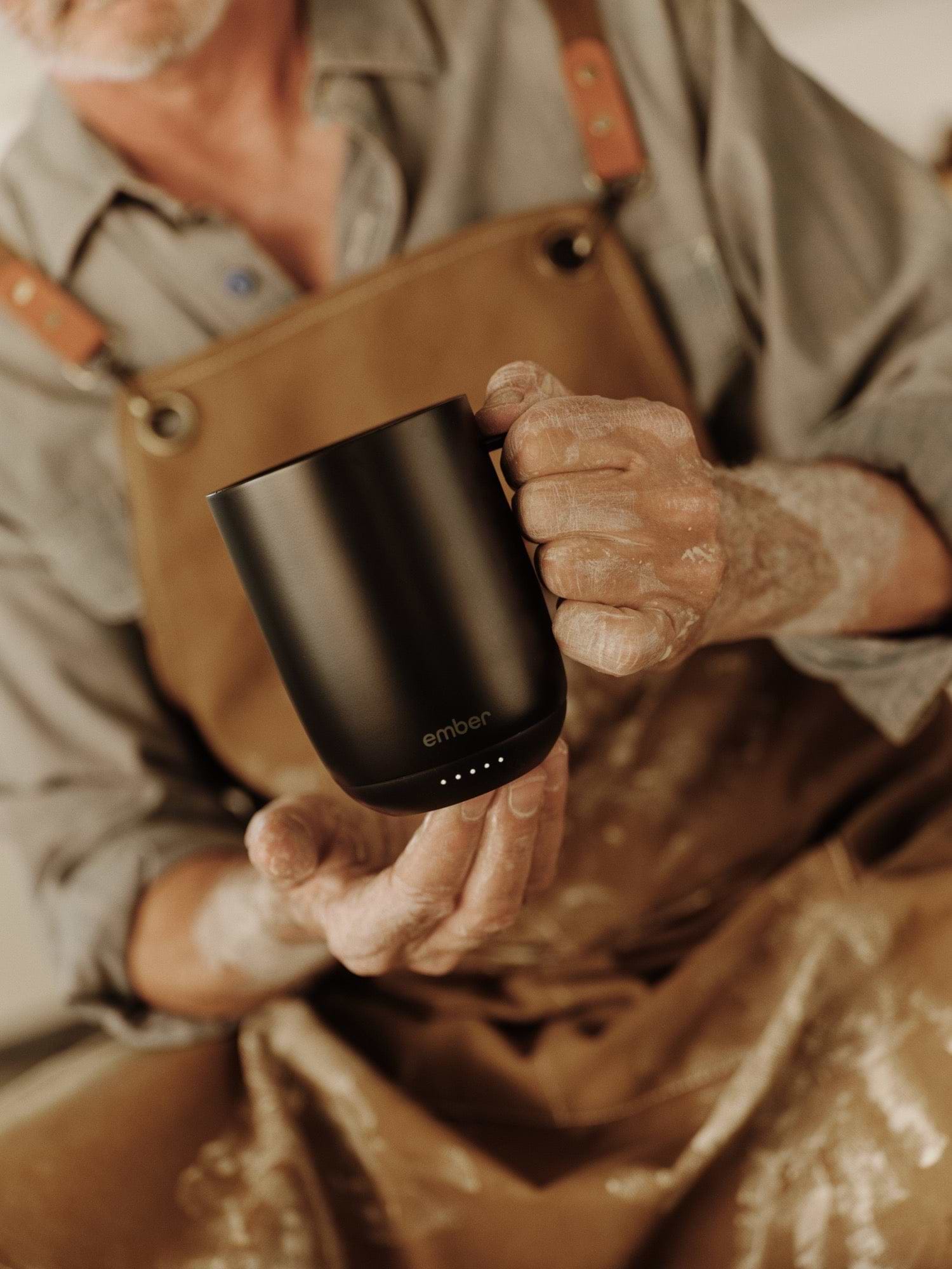 Setting the temperature on a black Ember Mug 3 in a pottery studio