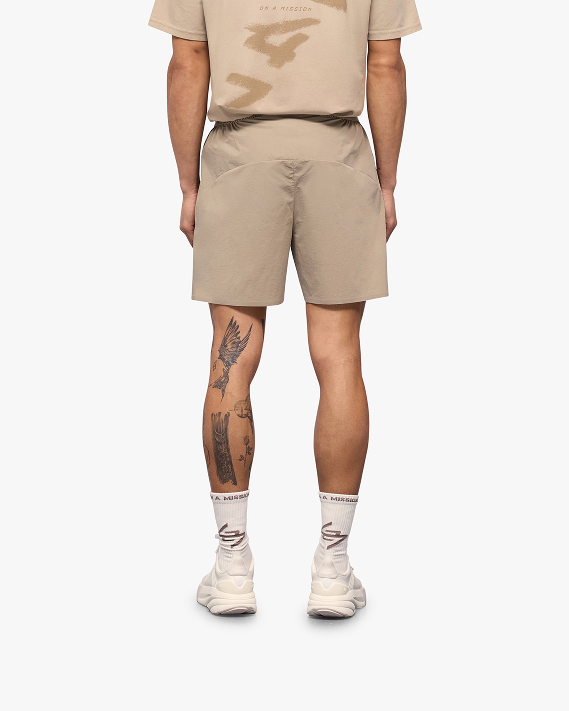 Man wearing grey shorts on a plain white background | 247 Training Shorts in Pebble | High intensity nylon spandex shorts with perforation detailing | 247 Shorts | Represent Clo