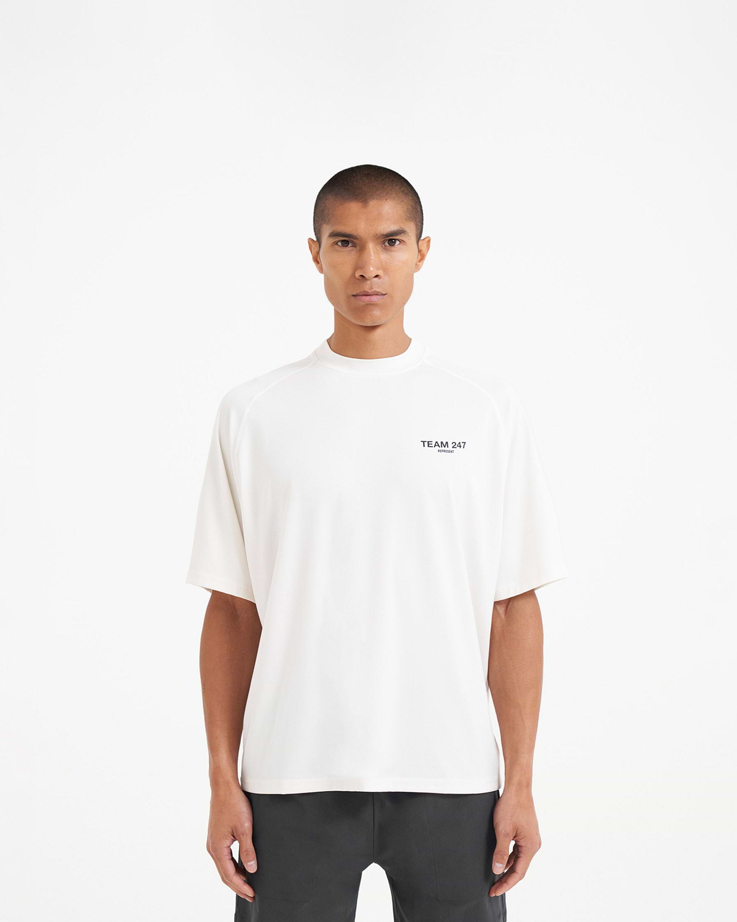 Man wearing an oversized white t-shirt on a plain white background | Team 247 Oversized T-Shirt in Flat White | Lightweight quick-dry gym t-shirt | 247 T-Shirts | Represent Clo