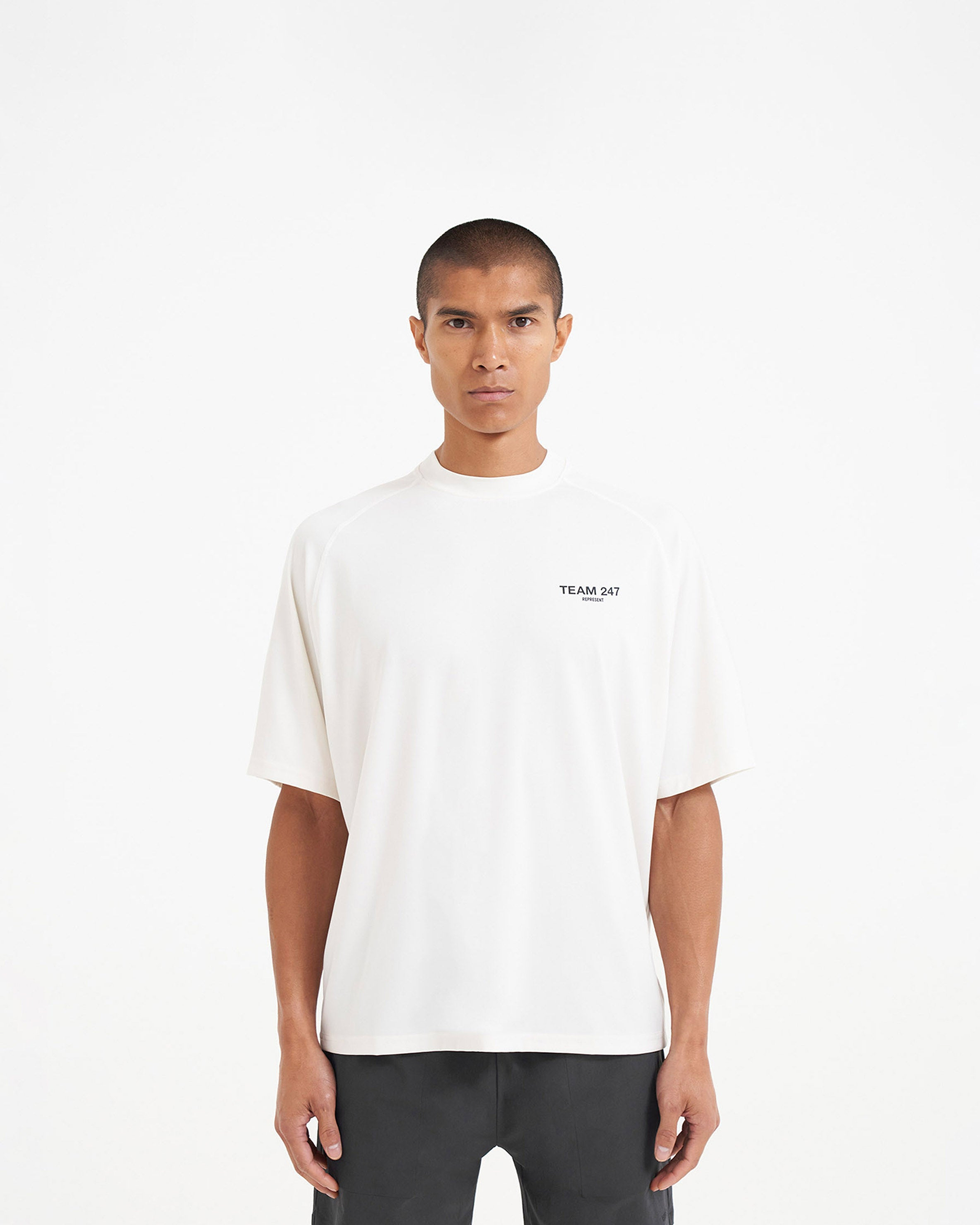 Man wearing an oversized white t-shirt on a plain white background | Team 247 Oversized T-Shirt in Flat White | Lightweight quick-dry gym t-shirt | 247 T-Shirts | Represent Clo
