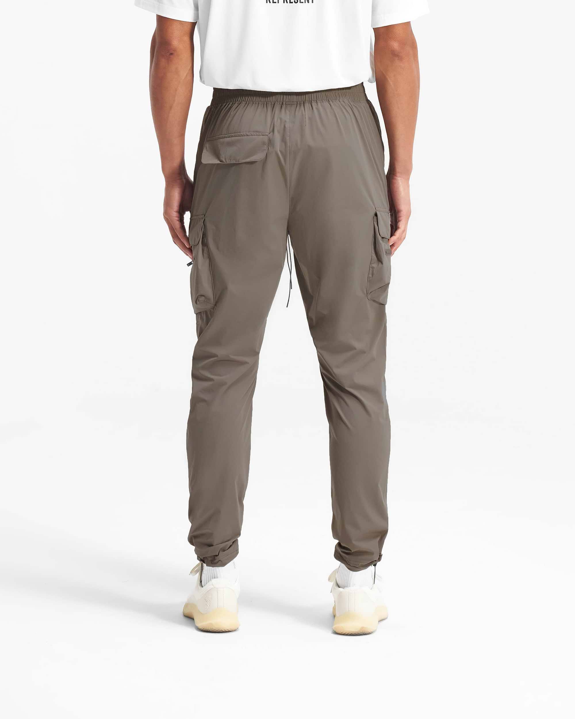 Man wearing olive cargo pants on a plain white background | 247 Pant in Olive | Cargo pants with spacious pockets and adjustable waistband | 247 Pants | Represent Clo