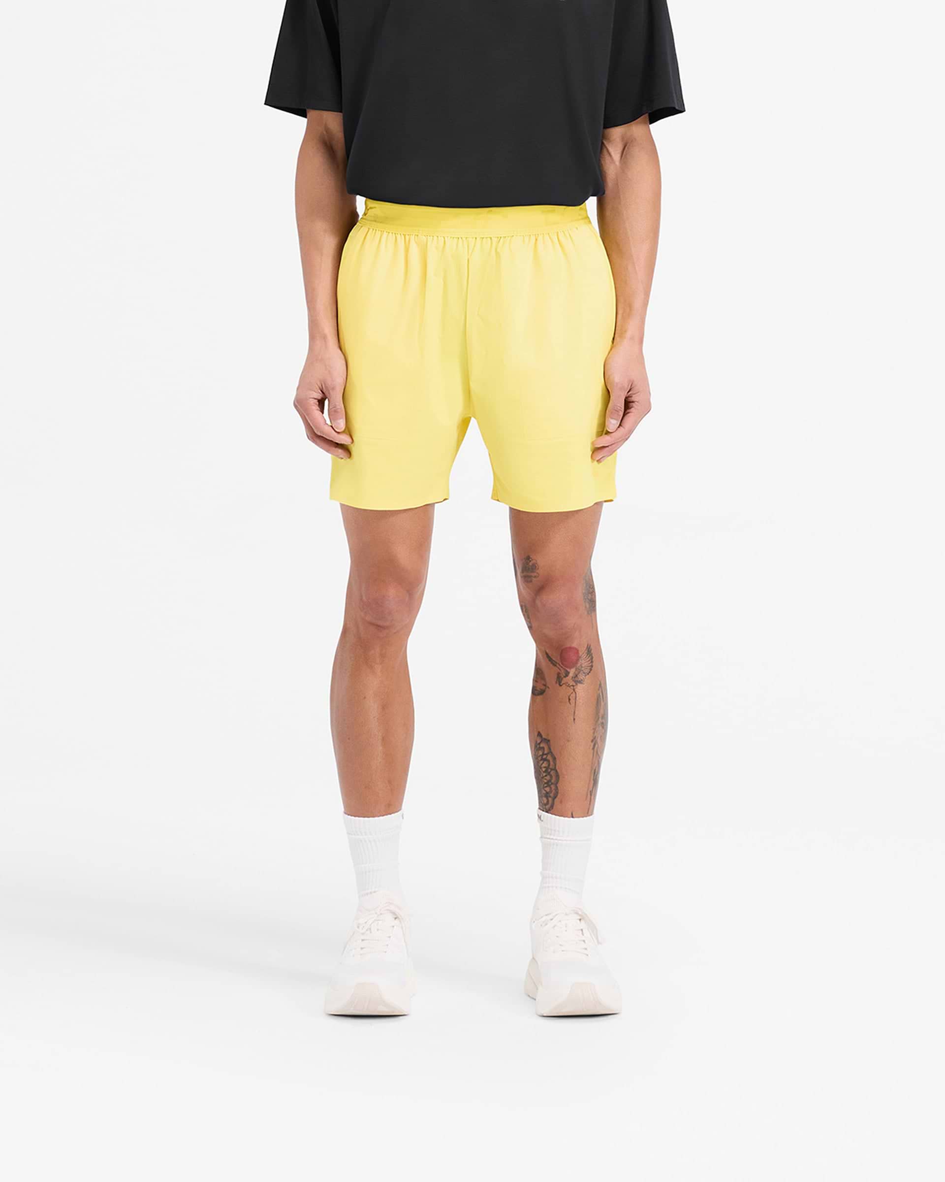 Man wearing yellow training shorts on a plain white background | Team 247 Fused Shorts in Lemon | Gym shorts with internal drawcords and quick drying fabric | 247 Shorts | Represent Clo