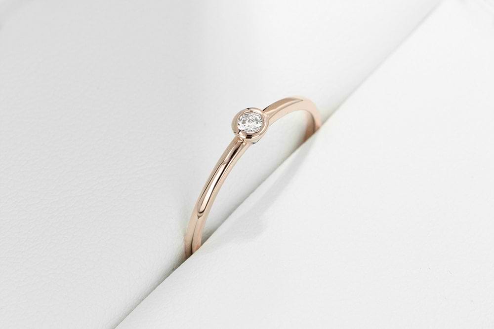 Simple and sleek stackable band with a small bezel set recycled diamond at the center