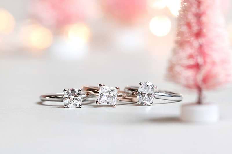 Three affordable solitaire engagement rings containing  round cut princess cut and oval cut lab grown diamonds