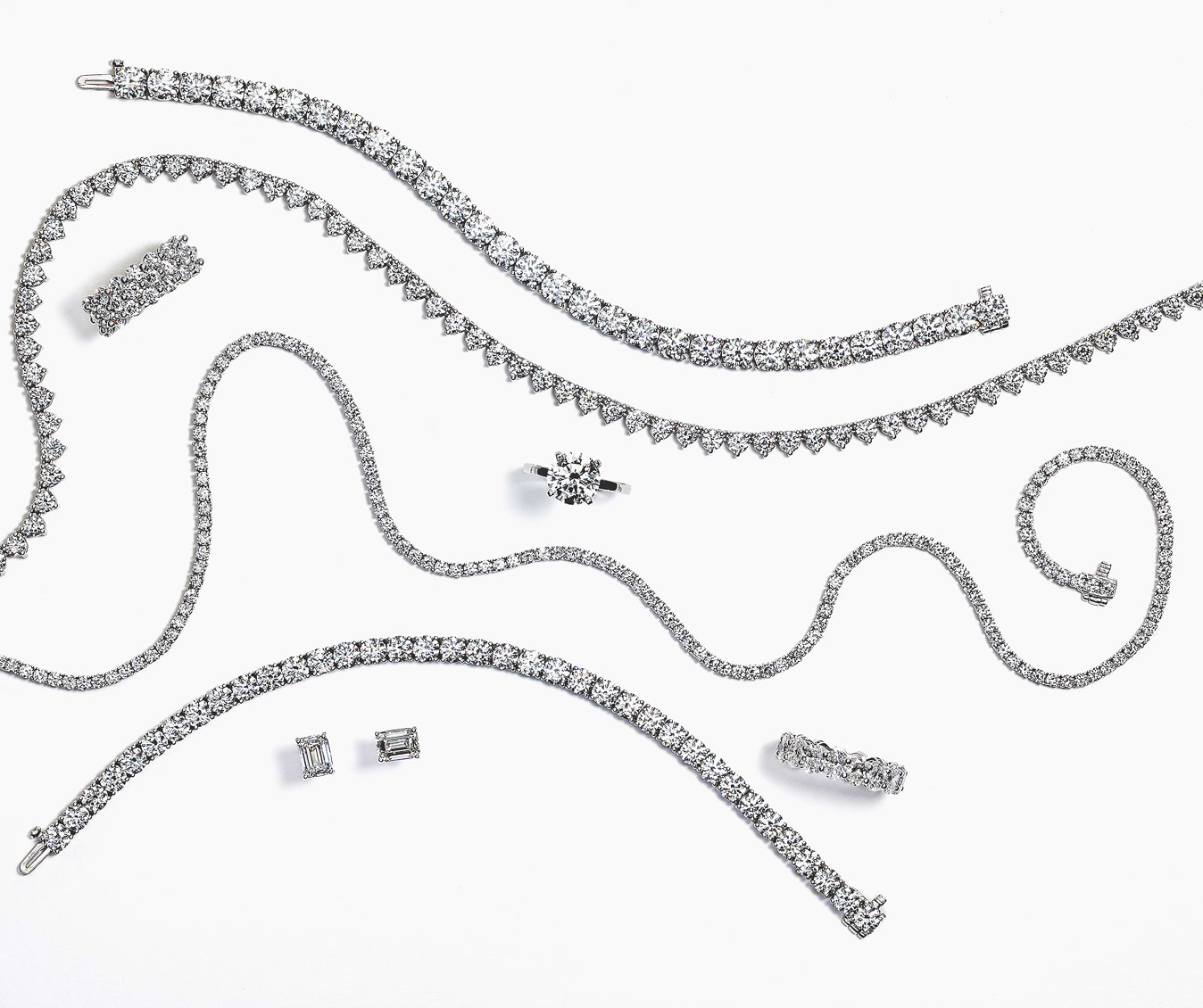 Collection of diamond jewelry including necklaces and earrings on a white background