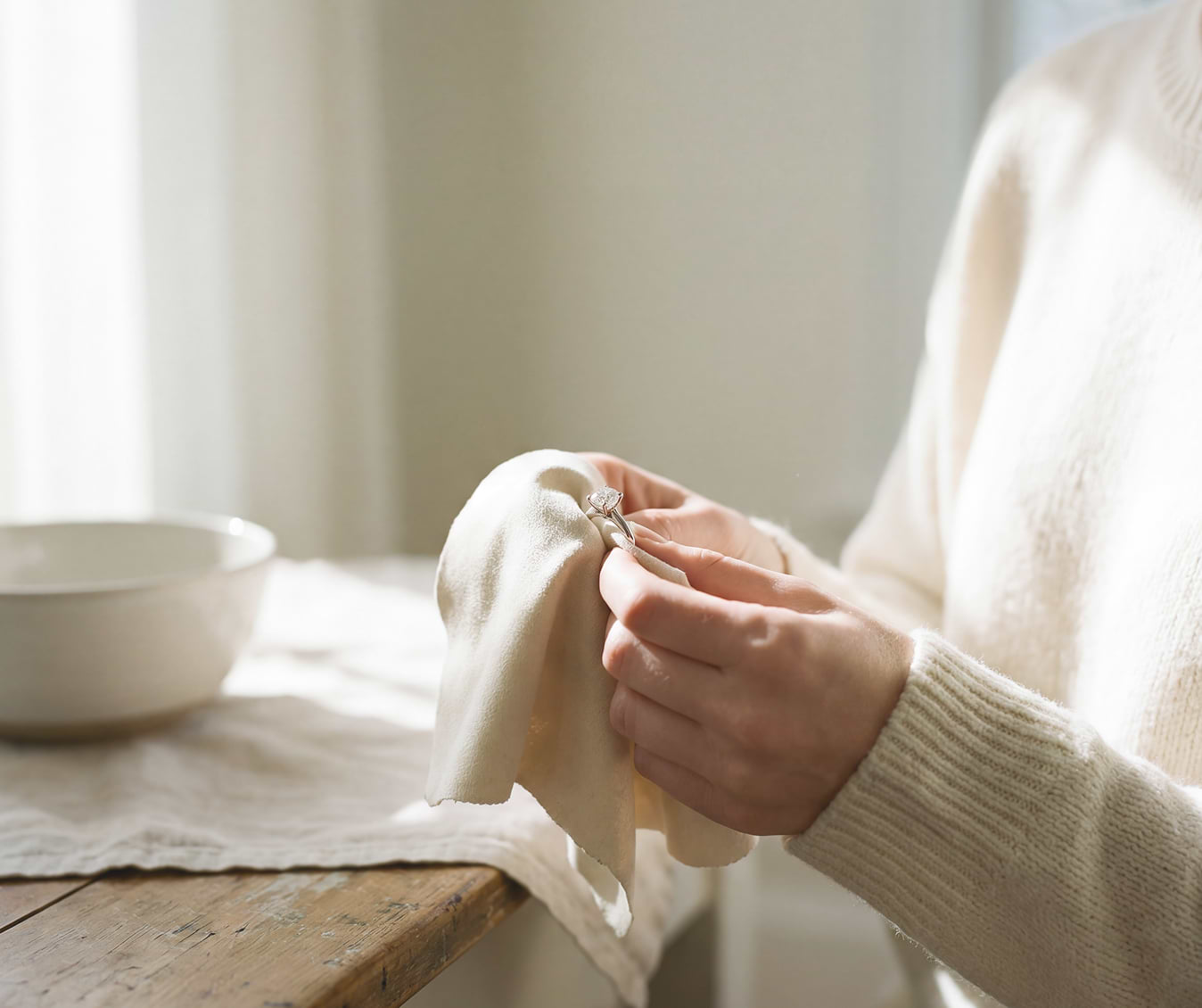 Woman cleaning her lab-grown diamond engagement ring with a soft cleaning cloth