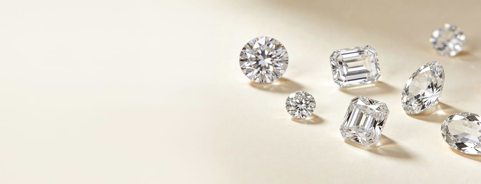 Collection of lab-grown diamonds in various cuts on a light beige background