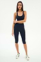 A woman stands facing forward in the SPLITS59 Ella Airweight Bra in Indigo/Bright Yellow, paired with matching capri leggings and white sneakers, all against a plain white background.