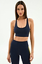A woman wears the SPLITS59 Ella Airweight Bra in Indigo/Bright Yellow with matching high-waisted leggings, featuring yellow side stripes and stretch fabric, standing against a plain white background.