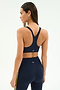 A woman is seen from the back wearing the SPLITS59 Ella Airweight Bra in Indigo/Bright Yellow, paired with matching high-waisted leggings featuring yellow stripes, set against a plain light background.