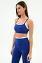 A woman models the SPLITS59 Elliah Airweight Double Layer Bra in Cobalt/White with matching high-waisted nylon spandex leggings, standing against a plain white background.
