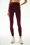 A person is wearing SPLITS59 Clare High Waist Rigor 7/8 leggings in Dark Cherry/Blush, featuring a sculpting high-waisted fit, paired with white sneakers and standing against a plain light background.
