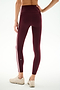 A person wearing SPLITS59 Clare High Waist Rigor 7/8 leggings in Dark Cherry/Blush, featuring a sculpting fit and white side stripe, paired with beige sneakers, standing on a white background and shown from the back.