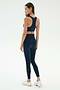 A woman wears the SPLITS59 Lexi Rigor Bra in Indigo/Blush with matching leggings and white sneakers, standing against a plain white background, facing away and looking to the side.