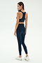 A woman wears the SPLITS59 Lexi Rigor Bra in Indigo/Blush with matching leggings and white sneakers, standing against a plain white background, facing away and looking to the side.