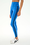 A model wears the SPLITS59 Ella High Waist Airweight 7/8 leggings in Classic Blue/Indigo, featuring black side stripes, paired with white athletic shoes and stands against a plain white background.