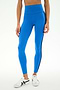 A person wearing SPLITS59 Ella High Waist Airweight 7/8 leggings in Classic Blue/Indigo, paired with white sneakers, stands against a plain light background.