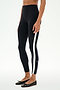 A person wears SPLITS59 Miles High Waist Rigor 7/8 leggings in black/white with a white side stripe and black ballet flats, standing against a plain white background.