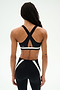 Person stands with back to camera, wearing the SPLITS59 Miles Rigor Bra in Black/White, featuring crisscross straps, paired with matching black leggings accented in white.