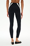 Model wears SPLITS59 Miles High Waist Rigor 7/8 leggings in Black/White, featuring white side panels and black flat shoes, standing with back to camera against a plain white background.
