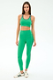 A woman faces forward wearing SPLITS59 Amber Airweight High Waist 7/8 leggings in Spearmint/Military and a matching sports bra, paired with white sneakers with green stripes, on a plain white background.