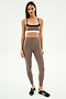 A woman stands against a white background wearing the SPLITS59 Scottie Airweight Bra in Lentil/Black.