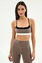 A woman models the SPLITS59 Scottie Airweight Bra in Lentil/Black, featuring black and white accents and matching high-waisted leggings, made from a soft nylon-spandex blend, against a plain white background.
