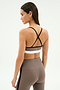 A woman stands with her back to the camera, wearing the SPLITS59 Scottie Airweight Bra in Lentil/Black and matching high-waisted leggings.