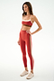Woman wearing the SPLITS59 Scottie Airweight Bra - Terracotta/Creme with matching high-waisted striped leggings and beige sneakers, standing against a white background.