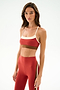 Woman wearing the SPLITS59 Scottie Airweight Bra - Terracotta/Creme with matching high-waisted leggings, standing against a plain white background.
