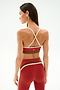 Woman faces away, wearing SPLITS59 Scottie Airweight Bra - Terracotta/Creme with matching high-waisted leggings on a plain light background.