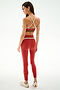 Woman facing away, wearing the SPLITS59 Scottie Airweight Bra - Terracotta/Creme with matching leggings and white shoes, on a plain white background.