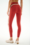 Model wearing SPLITS59 Emerson Airweight High Waist 7/8 - Terracotta/Creme leggings with white and tan side stripes, beige sneakers, facing away against a white background.