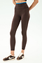 A person wears SPLITS59 Dual High Waist Airweight 7/8 leggings in Dark Chocolate/Classic Blue, featuring a blue waistband, paired with brown Nike sneakers, standing against a plain white background.